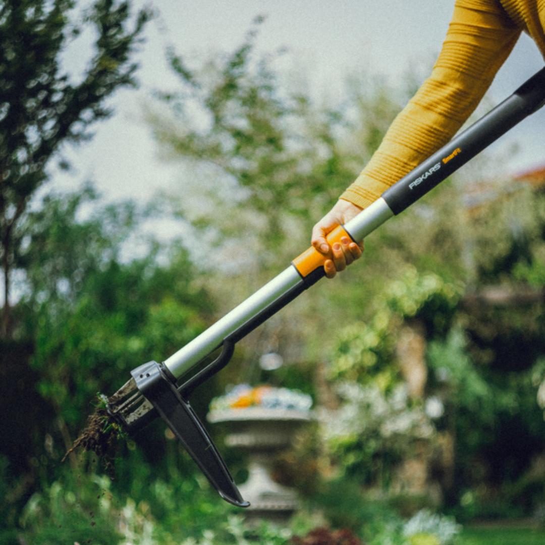 Person using a garden tool with a blurred garden background