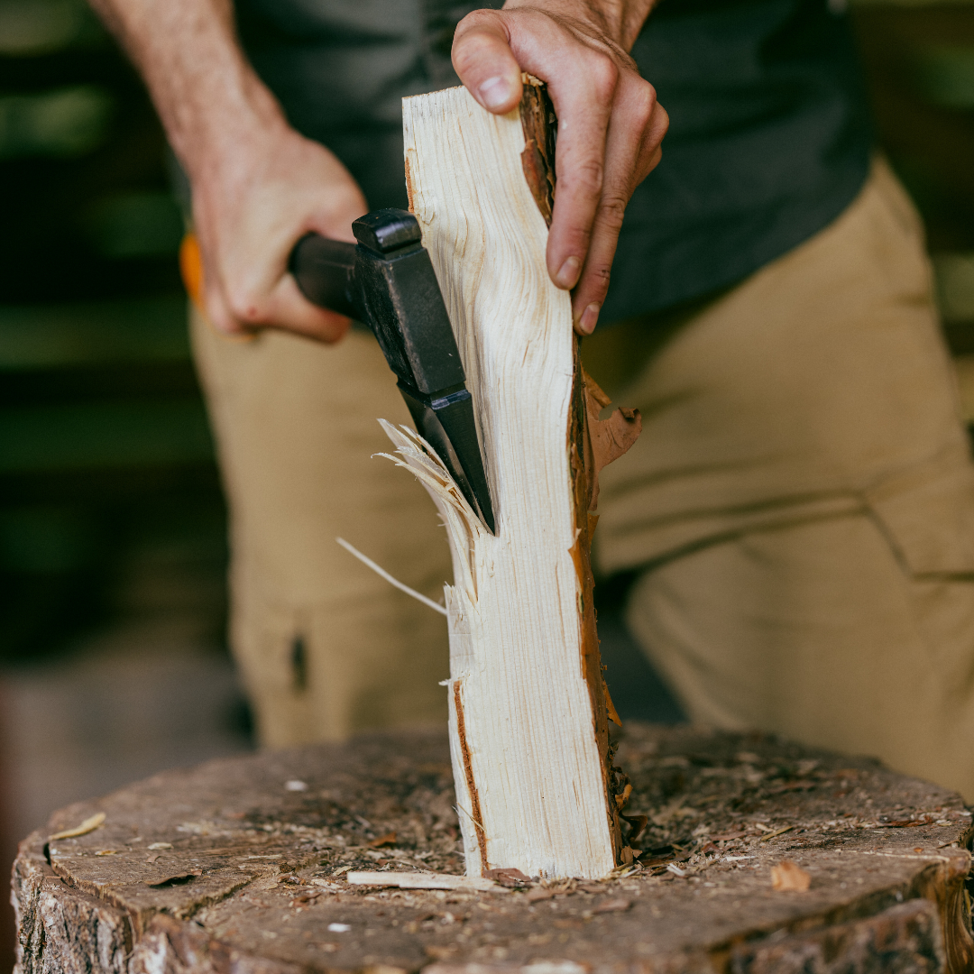 Person splitting wood with a knife on a tree stump outdoors