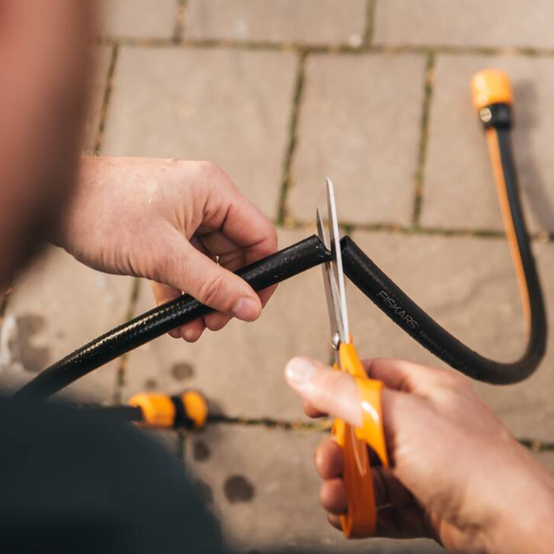 Fiskars universal scissors cutting a hose for DIY tasks
